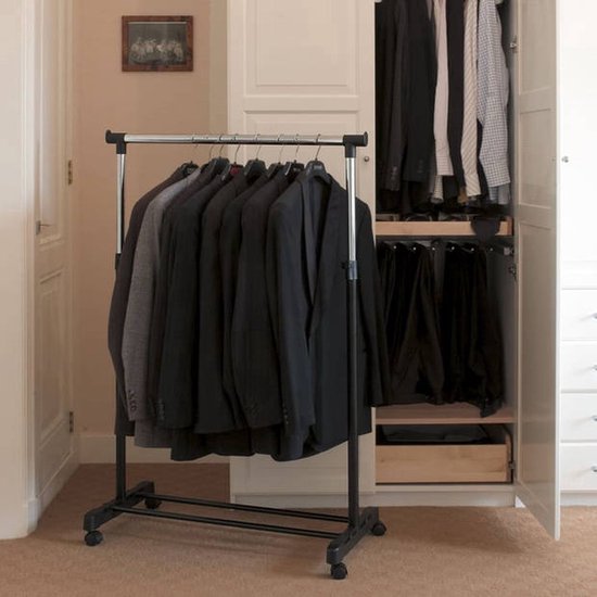 Kledingrek met donkere herenpakken en een open kast met kleding.