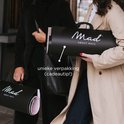 Twee personen dragen zwarte verpakkingen met 'Mad About Mats' logo. De verpakking is een cadeau-tip.
