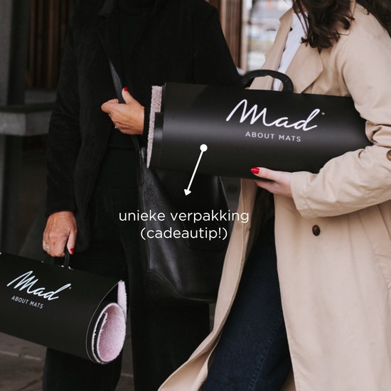 Twee personen dragen zwarte verpakkingen met 'Mad About Mats' logo. De verpakking is een cadeau-tip.