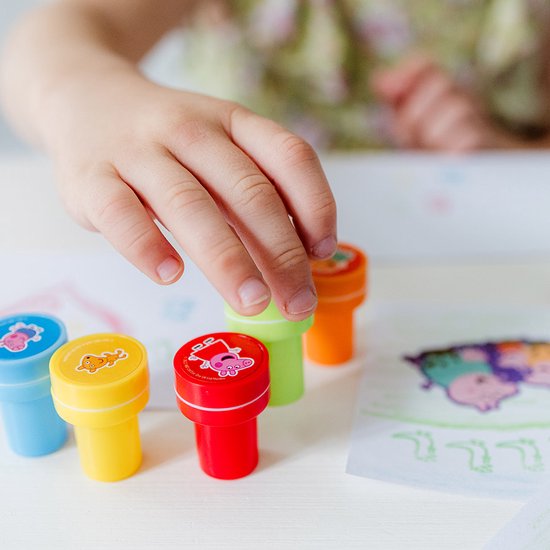 De hand van een jong kind pakt een rode Peppa Pig stempel, vier andere stempels staan op het papier.