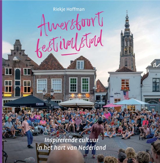 Boek 'Amersfoort festivalstad' met tekst en een foto van een druk stadsplein met mensen, gebouwen en een toren.