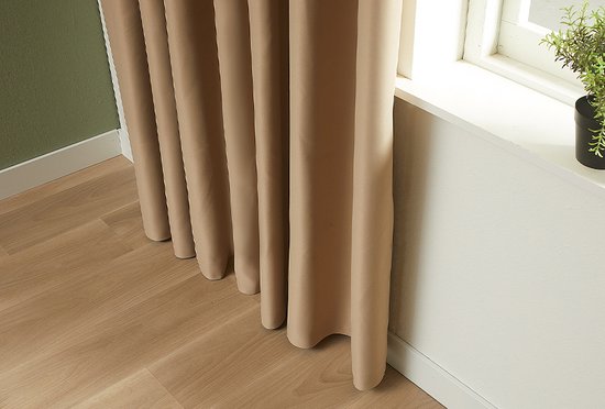 Taupekleurige gordijnen die tot op de houten vloer vallen.