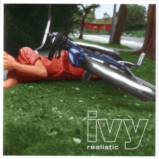 Een persoon in een rood geruite blouse ligt op het gras naast een omgevallen fiets. De tekst 'ivy realistic' is onderaan de afbeelding.