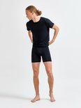 Man met lang blond haar draagt een zwarte t-shirt en zwarte boxer, hij trekt zijn t-shirt recht.