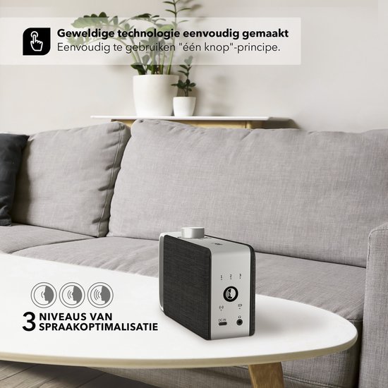 Zwarte luidspreker met zilverkleurig handvat op een witte tafel. De achterkant heeft knoppen en aansluitingen. Tekst: 'Geweldige technologie eenvoudig gemaakt' en '3 niveaus van spraakoptimalisatie'.