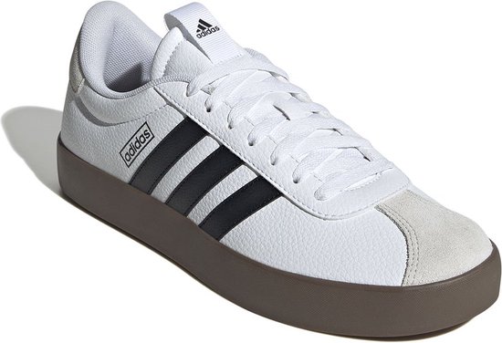 Witte sneaker met zwarte Adidas strepen, bruine zool en beige neus, op witte achtergrond.