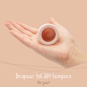 Main tenant une coupe menstruelle rose pâle ouverte, économisant jusqu'à 264 tampons par an.