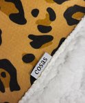 Detail van de zachte, witte sherpa voering van een plaid met luipaardprint en een Cosas label.