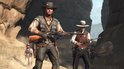 Twee mannen met geweren in de woestijn, de ene met een cowboyhoed, de andere met een hoed.