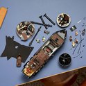 Un modèle LEGO du navire pirate du Capitaine Jack Sparrow avec des voiles noires et des figurines sur un fond bleu.