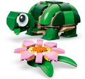 Groene LEGO-schildpad met grote ogen, naast een roze waterlelie.