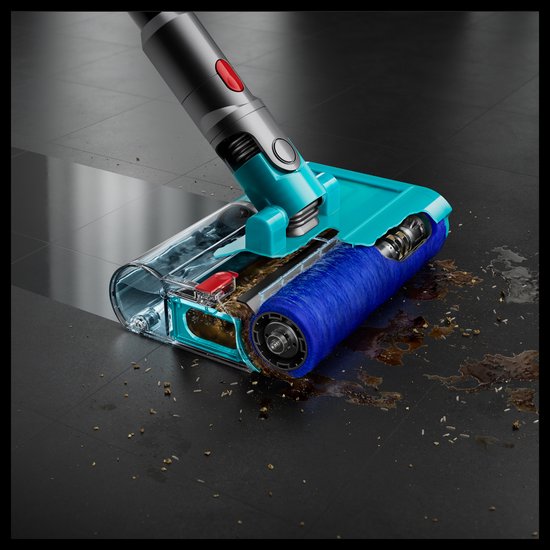De turquoise mond van een Dyson stofzuiger met blauwe borstel verwijdert kruimels en vlekken van een donkere tegelvloer.
