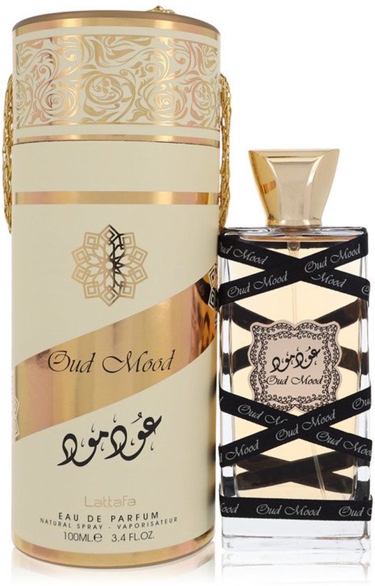 Oud Mood parfumfles met gouden dop, omwikkeld met zwart lint met "Oud Mood" erop. Bijpassende cilinderverpakking met gouden opdruk.