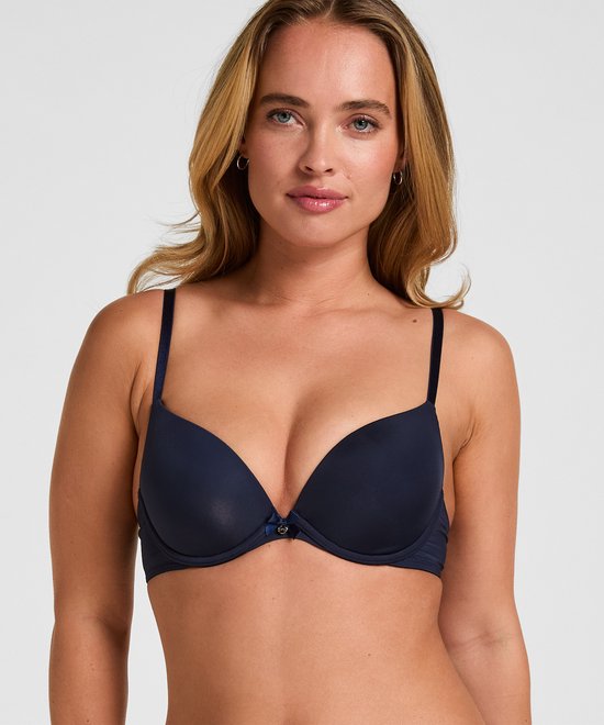 Model draagt een marineblauwe Plunge beugel bh met voorgevormde cups en een strikje middenvoor.