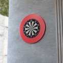 KOTO King Classic dartbord met rode rand, gemonteerd op een betonnen muur.