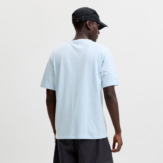 Man met donkere huid in lichtblauwe t-shirt en grijze korte broek, de achterkant.