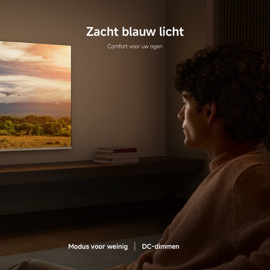 Jonge man kijkt tv in een donkere kamer. Het tv-scherm toont een landschap met zonsondergang.