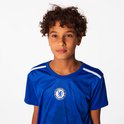 Jongen met krullend haar, poseren in een blauw Chelsea FC voetbalshirt met witte schouderstrepen en een leeuw print.
