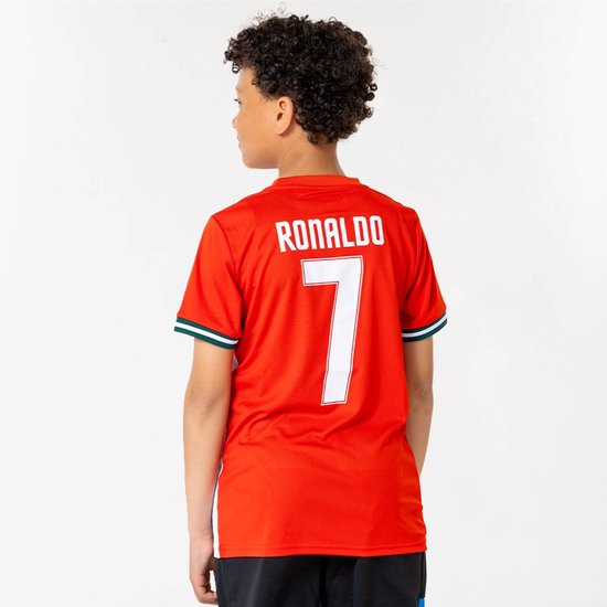 Petit garçon aux bras croisés, portant l'arrière d'un maillot de football rouge avec 'RONALDO 7' en lettres blanches.