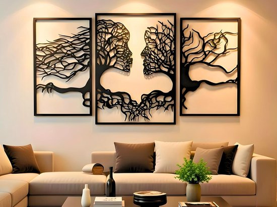 Décoration murale triptyque de visages d'arbres noirs se faisant face, au-dessus d'un canapé beige.