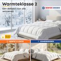 Wit dekbed op een bed bij een raam met sneeuw (winter) en een ander bed bij een raam met herfstbladeren.