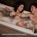 Koppel geniet van een bad in een opblaasbare Tubble badkuip met champagne.