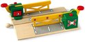 Houten magnetische treinbaanovergang van BRIO met twee groen-gele slagbomen, een rode bedieningsknop en een wit handvat.