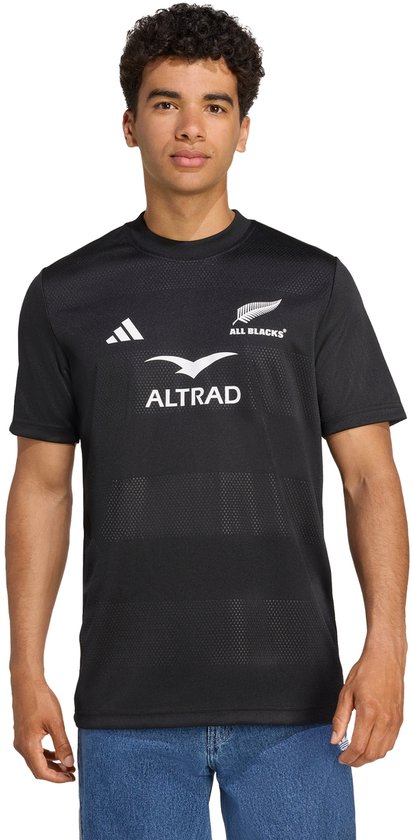 Zwarte performance shirt met logo's en 'ALL BLACKS' tekst. Gedragen door een man.