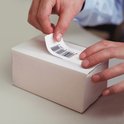Handen brengen een label met barcode aan op een wit doosje.