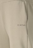 Zakdetail van beige trainingsbroek met zwart logo.