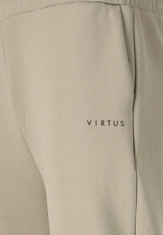 Zakdetail van beige trainingsbroek met zwart logo.