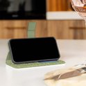 Telefoon in een groen hoesje met bladerpatroon, staand op een tafel.