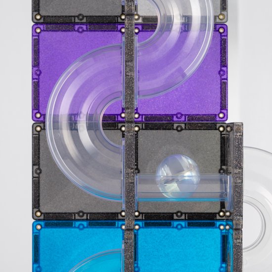 Close-up van een Connetix knikkerbaan met paarse en grijze glittertegels, transparante buizen en een glimmende knikker.