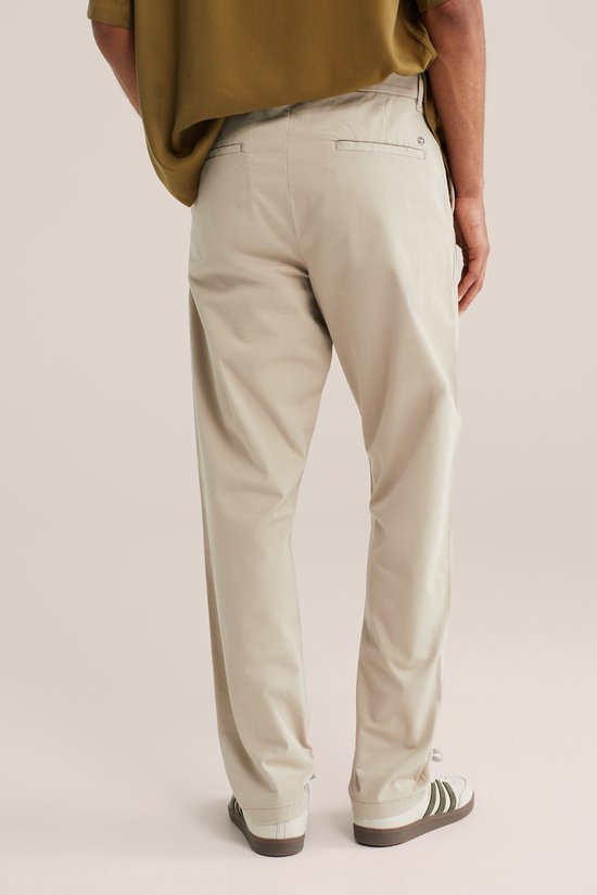Model van achteren in een beige chino broek en olijfgroen hemd.
