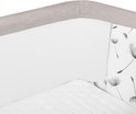 Close-up van beige co-sleeper met gaas en paardenbloemenprint.