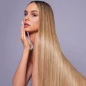 Model met lang, steil blond haar en verzorgde handen, aanrakend haar gezicht.