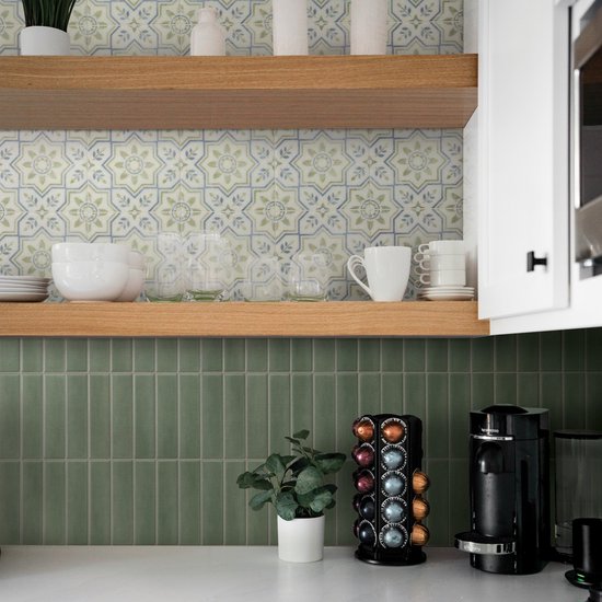 Mosgroene, verticale tegels bedekken de achterwand van een keuken met houten planken en een Nespresso-apparaat.