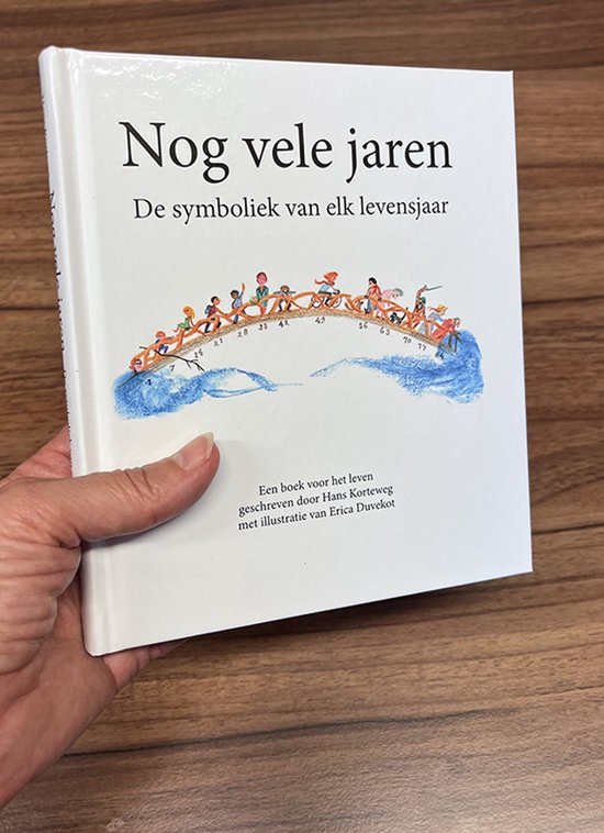 Een hand die een boek vasthoudt met de titel 'Nog vele jaren' en een illustratie van kinderen op een brug.