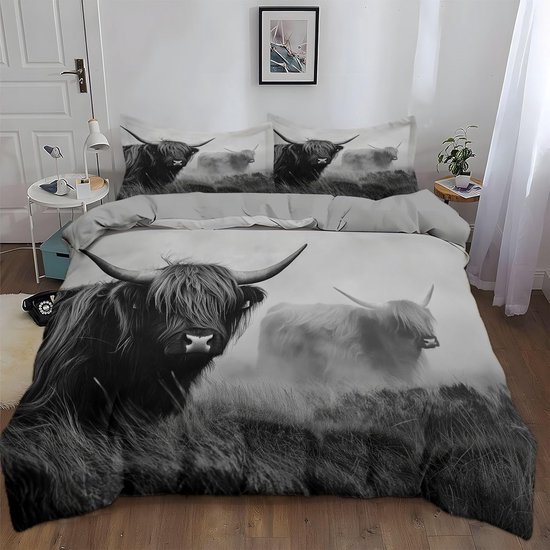 Tweepersoonsbed met zwart-wit dekbedovertrek met Schotse hooglander in een weide.