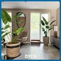Stores vénitiens gris clair dans un salon avec de grandes plantes, un fauteuil et des meubles en bois.