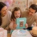 Vrolijk verjaardagsfeestje met ouders en dochter die een prinsessenboek vasthoudt.