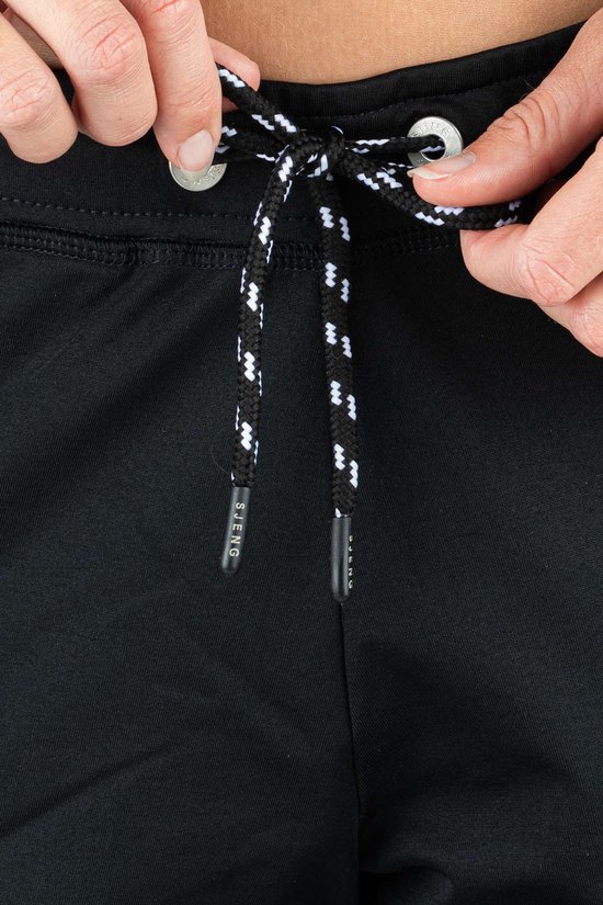 Sluiting van een zwarte trainingsbroek met zwart-witte veter en zilverkleurige veterogen.