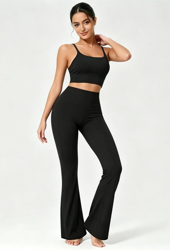 Vrouw in zwarte crop top en flare yoga broek, staande pose.