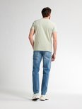 Man van achteren gezien in een lichtgroen T-shirt en lichtblauwe jeans.