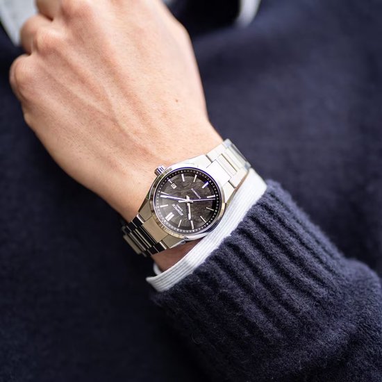 Close-up van een man die een zilverkleurig Edifice Casio horloge draagt om zijn linkerpols.