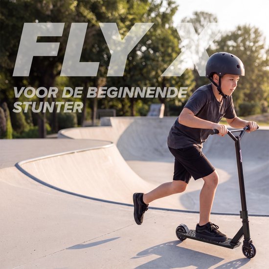 Jongen met helm rijdt op zwarte stuntstep in skatepark. "FLY X VOOR DE BEGINNENDE STUNTER".