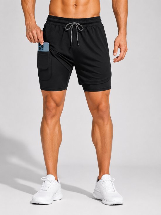 Mannequin portant un short de sport noir, plaçant un téléphone dans la poche latérale. Baskets blanches sportives.