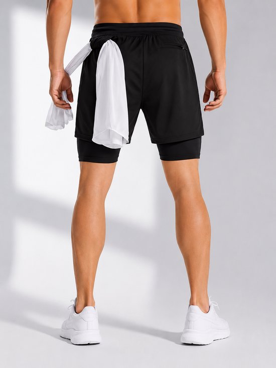 Vue arrière d'un homme portant un short de sport noir avec une serviette blanche dans la boucle arrière.