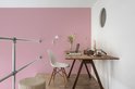 Bureau met laptop en decoratie tegen een roze muur.
