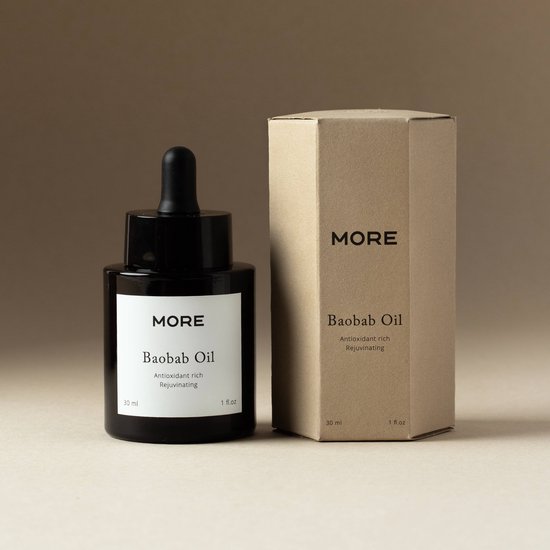 Een zwart flesje MORE Baobab Olie met een wit label, naast een bijpassend bruin kartonnen doosje.